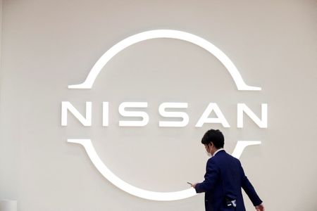 ５月１３日、   午前の東京株式市場で、日産自動車株が急伸している。同社ロゴの前を歩く男性。２０２１年１１月、横浜市で撮影（２０２５年　ロイター/Androniki Christodoulou）