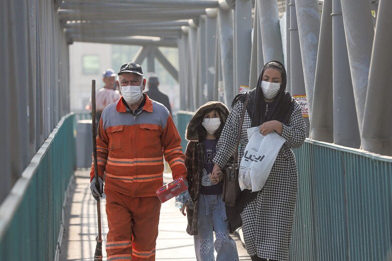 大気汚染対策のマスクを着けて橋を渡るテヘラン市民（11月27日）　FATEMEH BAHRAMIｰANADOLU/GETTY IMAGES