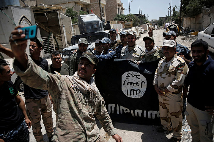 昨年6月、モスルで奪ったISISの旗を掲げるイラク軍兵士　Alkis Konstantinidis-REUTERS