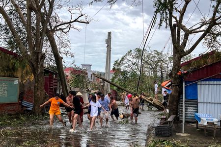 　ベトナム計画投資省は台風１１号（ヤギ）による被害額がおよそ１６億ドルに上り、経済成長率を押し下げる可能性があるとの見方を示した。写真は倒木をロープで取り除く人々。８日ハイフォンで撮影（２０２４年　ロイター/Minh Nguyen）