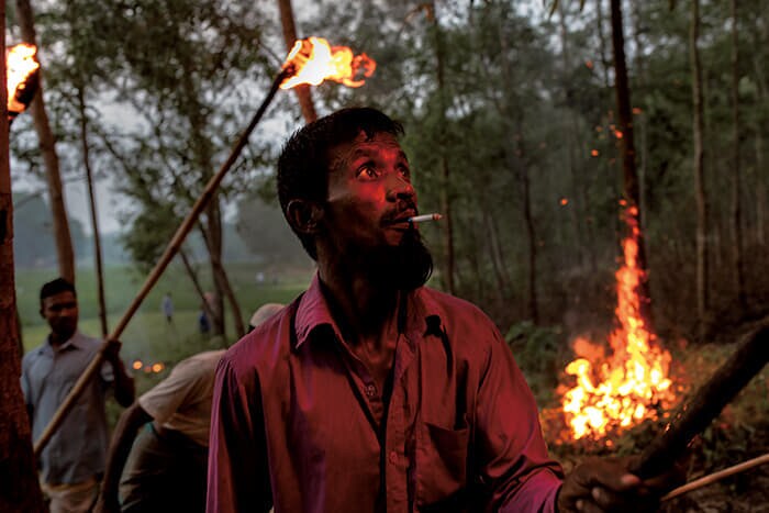 手に手に松明を持ち、ゾウを水田から追い払おうとする村人（22年4月)