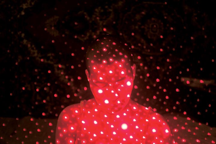赤いレーザーポインターを使って化学療法で経験した痛みや感情を表現する。骨は火が出るように痛く、頭がうまく働かない状態も表している