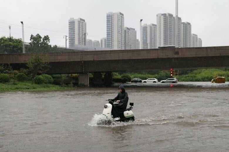 写真は、台風１３号（ドルフィン）による大雨で冠水した道路を走るスクーター。中国河南省鄭州市で１２日撮影。REUTERS/Tingshu Wang