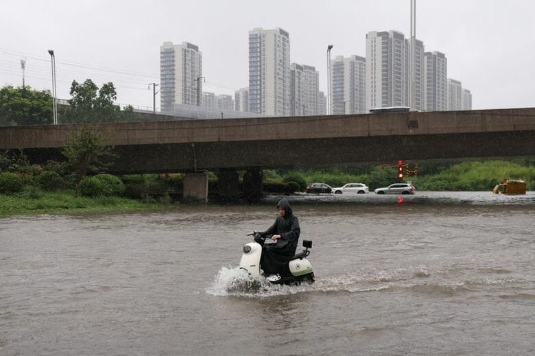 写真は、台風１３号（ドルフィン）による大雨で冠水した道路を走るスクーター。中国河南省鄭州市で１２日撮影。REUTERS/Tingshu Wang