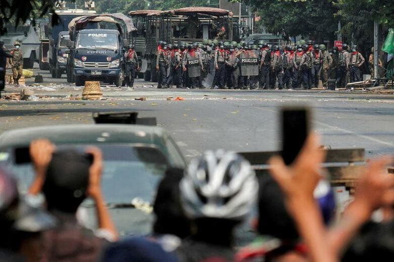 ミャンマーの軍事政権が街頭での抗議行動の沈静化を図る一方で、ソーシャルメディア（SNS）上でもそれと並行する戦いが展開されている。写真は道を挟んでにらみ合う警察と軍事クーデターに反対する人々、3月にマンダレーで撮影された提供写真（2021年　ロイター）