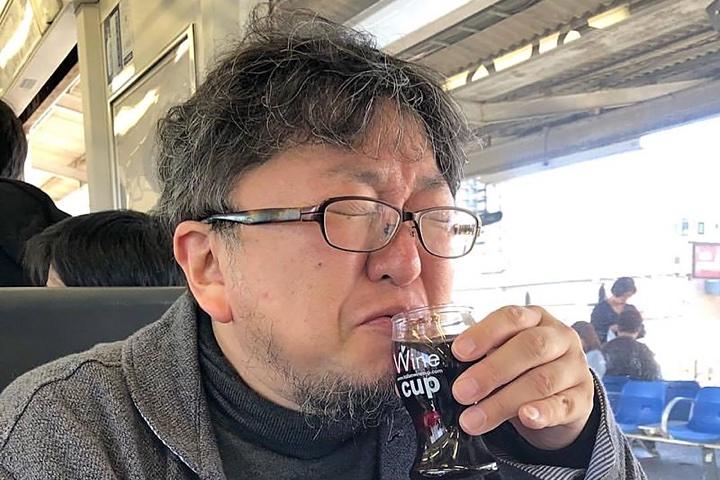 旅先で飲むお酒も大好き。移動中の電車でカップワインをキューっと飲む樋口監督。