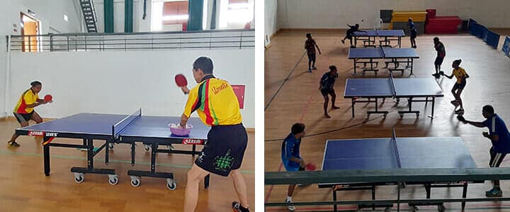 (左)トミー選手に指導する髙嶋さん(右)卓球台が4台並ぶ体育館