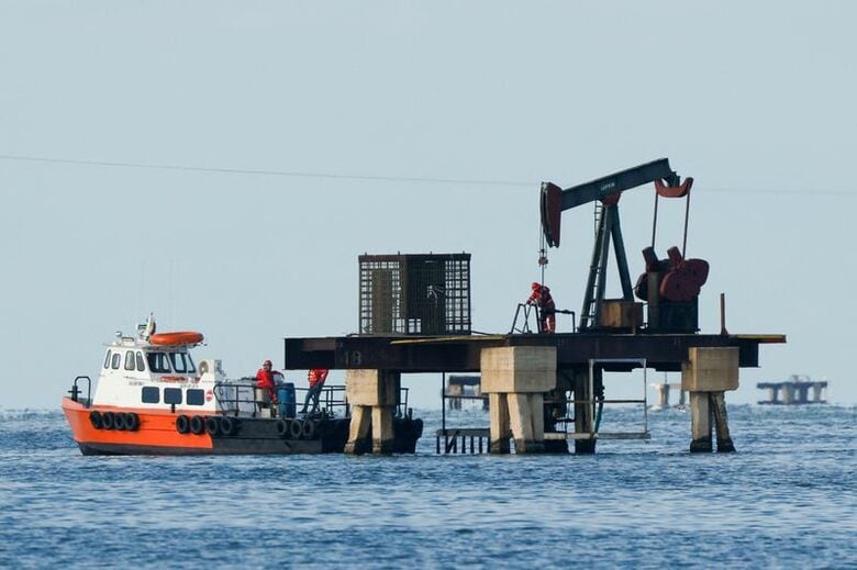 ベネズエラのカビマスにあるマラカイボ湖で、ポンプジャックで作業するベネズエラ国営石油会社PDVSAの従業員。1月27日撮影。REUTERS/Leonardo Fernandez Viloria