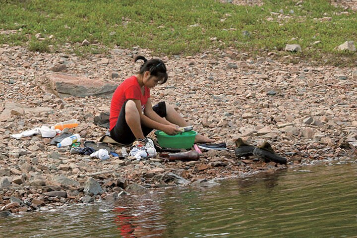 中朝国境の鴨緑江で靴を洗う女性　THOMAS PETERーREUTERS