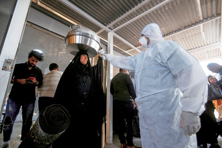 イランとイラクの国境を通過する人の体温検査をする医療スタッフ　ESSAM AL SUDANI-REUTERS