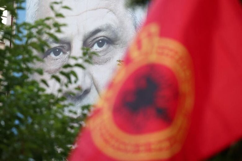 写真はコソボ元大統領ハシム・サチ被告の肖像画。2025年8月、同国プリシュティナで撮影。REUTERS/Florion Goga
