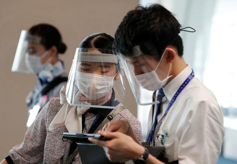 緊急事態宣言の解除後、航空旅客に需要回復の兆しが見えつつある。写真は４日、羽田空港でフェイスシールドなどを着けて乗客を案内する全日空の従業員（２０２０年　ロイター/Kim Kyung-Hoon）