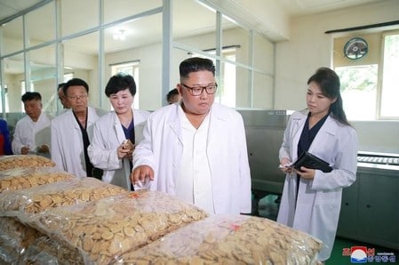 　７月２７日、韓国国防省は、北朝鮮と韓国が７月３１日に両国の軍事境界線にある板門店で軍事協議を行うことで合意したと明らかにした。写真は食品工場を視察する金委員長(中央）と李夫人(右）。朝鮮中央通信提供(２０１８年　ロイター)
