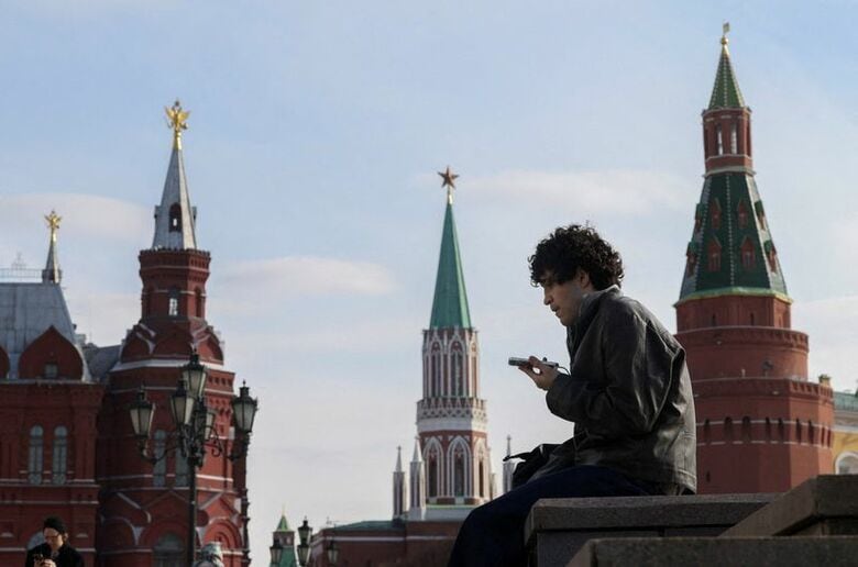 写真はモスクワ中心部で携帯電話を見る男性。3月17日、モスクワで撮影。REUTERS/Ramil Sitdikov