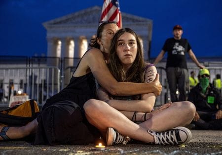 　６月２７日、米連邦最高裁が人工妊娠中絶を憲法上の権利と認める１９７３年の「ロー対ウェイド判決」を覆す判断を下したことを受け、中絶を巡る法廷闘争の舞台は州裁判所に移った。写真は米首都ワシントンの最高裁前に座る母子。２６日撮影（２０２２年　ロイター/Evelyn Hockstein）