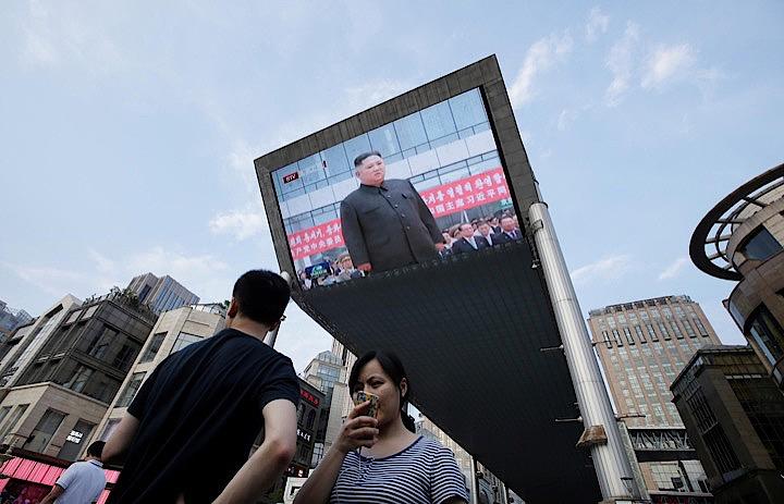 北朝鮮の金正恩朝鮮労働党委員長と中国の習近平国家主席は、「深刻で複雑な」国際情勢の中、中朝関係を発展させることが両国や地域の平和に寄与するとの認識で一致した。写真は20日、金委員長が平壌で習主席を迎える様子のテレビ映像を眺める北京市民（2019年　ロイター/Jason Lee）