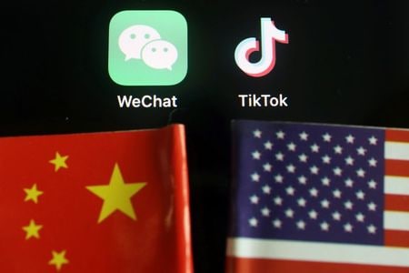 　８月７日、中国外務省は、トランプ米大統領が短編動画投稿アプリ「ＴｉｋＴｏｋ（ティックトック）」と対話アプリ「微信（ウィーチャット）」を運営する中国企業との取引を禁止する大統領令に署名したことに断固反対すると表明し、中国企業の合法的な権利と利益を守る方針を示した。写真は両アプリのロゴと、米中の国旗（２０２０年　ロイター／Florence Lo）