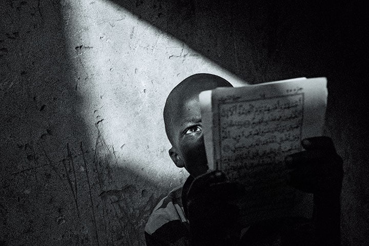 セネガルの首都ダカールにある宗教学校「ダーラ」でコーランを読む少年。彼らタリベと呼ばれる生徒たちは常に虐待の恐怖に怯えている