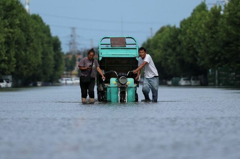 8月13日、中国河南省許昌市で、台風のあとに冠水した道路で車両を引く住民。 REUTERS/Tingshu Wang