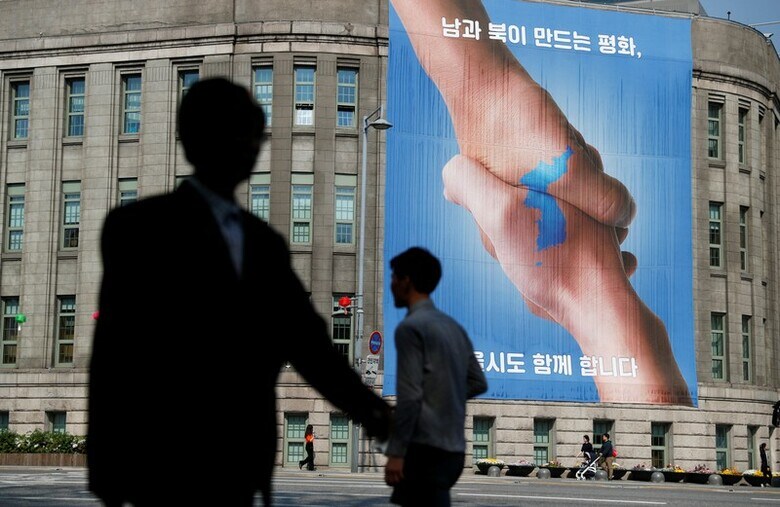 ４月２５日、南北統一は解決策なのか、あるいはそれこそが問題なのか──。北朝鮮と韓国の最近の緊張緩和によって、１９５０年代から分断している南北の統一に新たな可能性が浮上している。写真は南北首脳会談を控え、ソウル市役所に掲げられたバナー（２０１８年　ロイター/Jorge Silva）