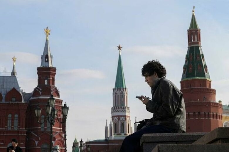 写真はモスクワ中心部で携帯電話を見る男性。3月17日、モスクワで撮影。REUTERS/Ramil Sitdikov