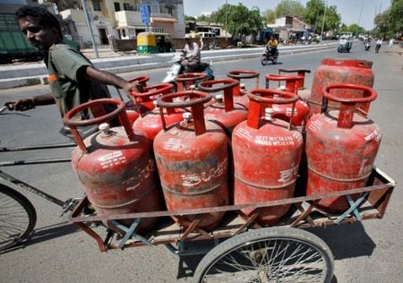 写真は調理用ガスボンベを積んだ三輪バイクを押す男性。2010年4月、インド西部のアーメダバードで撮影。REUTERS/Amit Dave