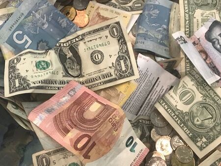 午後３時のドル／円は、前週末東京市場の午後５時時点とほぼ変わらずの１０３円半ば。米政府機関の閉鎖が回避されたことで、楽観ムードの下でドルと円がやや売られた。写真は米ドル紙幣（中央）など各国紙幣を組み合わせた写真イラスト。２０１８年７月１３日、カナダ・トロントで撮影。（２０２０年　ロイター／Chris Helgren）
