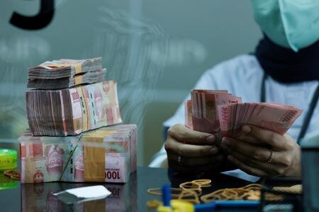 インドネシア中央銀行が２２日公表した第２・四半期の経常収支は２年ぶりの赤字となった。写真はインドネシアルピアの紙幣を数える両替所の職員。ジャカルタで昨年１０月撮影。（2023年 ロイター/Willy Kurniawan）