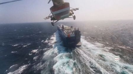 紅海で商業船３隻が攻撃された事件を受け、同海域を航行する船舶の戦争リスク保険料率が上昇し、商業船の安全運航への懸念も高まっていることが、海運・保険業界筋の話で４日分かった。写真は紅海で貨物船の近くを飛行するフーシ派のヘリコプター。１１月２０日の提供写真（２０２３年　ロイター／Houthi Military Media/Handout via REUTERS ）