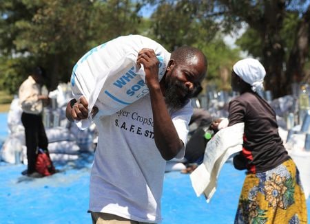 　１０月１５日、国連世界食糧計画（ＷＦＰ）は、アフリカ南部で数百万人が過去数十年で最悪の食糧危機に直面しており、資金不足によりＷＦＰの支援能力が逼迫する恐れがあると警告した。写真はＷＦＰからの食糧支援を集める人々。ジンバブエのブヘラ地区で３月撮影（２０２４　ロイター／Philimon Bulawayo）