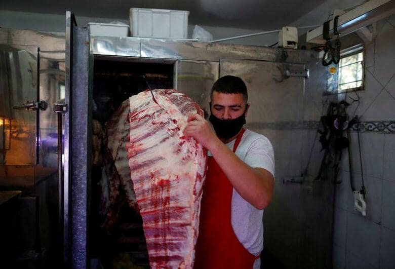 牛肉価格が世界的に高騰し、ステーキ好きの国アルゼンチンの首都ブエノスアイレスではメニューから牛肉が消え、米国では夏のバーベキューが台無しになりそうだ。ブエノスアイレスの精肉店で19日、冷蔵庫から牛肉を取り出す店員（2021年　ロイター/Agustin Marcarian）