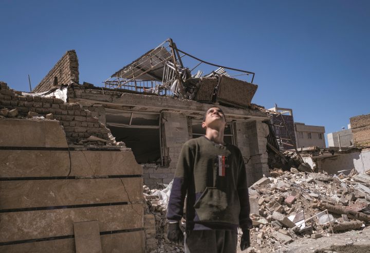 イランの首都テヘラン近郊で爆撃された住宅街に立つボランティア作業員　MORTEZA NIKOUBAZL-NURPHOTO-REUTERS