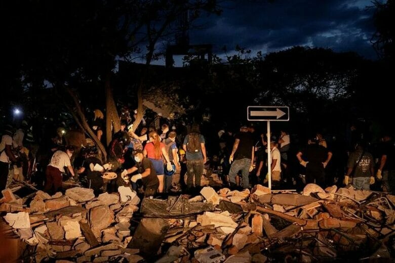 写真は倒壊した建物のがれきを掘り起こす人々。２０２６年８月１０日、コロンビアのカリで撮影。 REUTERS/Christian EscobarMora