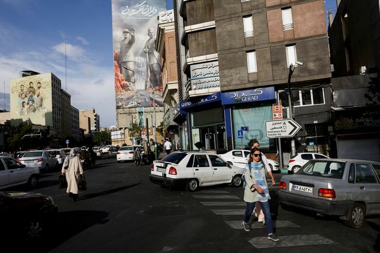 写真はホルムズ海峡に関する看板の前を通り過ぎる人々。5月17日、イランのテヘランで撮影。WANA提供。REUTERS