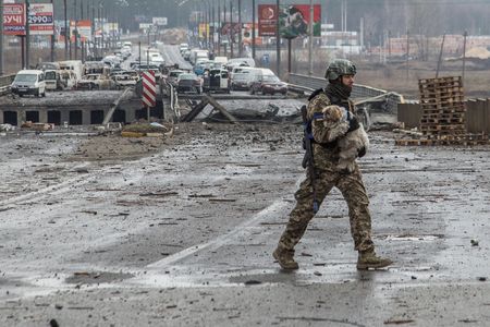 ４月１日、ウクライナ北部チェルニヒウの知事は、ロシア軍が撤退しつつあるが、完全撤退はしていないとし、砲撃などの可能性はまだあると述べた。写真は３月３０日、イルピンで犬を運ぶウクライナ兵（２０２２年　ロイター/Oleksandr Ratushniak）