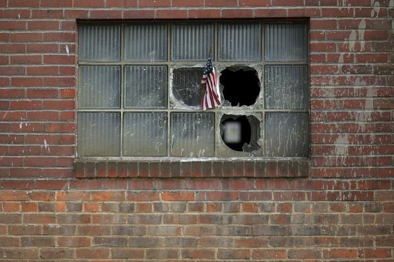 ２月１日、米鉄鋼業界の２５社・団体は、トランプ大統領に宛てた書簡で、米通商拡大法２３２条を用いて鉄鋼輸入に「包括的で広範な」制限を課すよう強く要請した。写真は割れた窓に米国旗が掲げられた閉鎖した鉄鋼所。ペンシルバニア州で２０１６年撮影（２０１８年　ロイター／Brian Snyder）