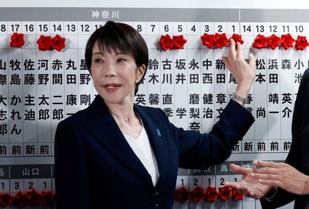 2月8日、東京都内の自民党本部で当選確実となった候補者の名前に造花を貼る高市早苗首相。代表撮影。REUTERS