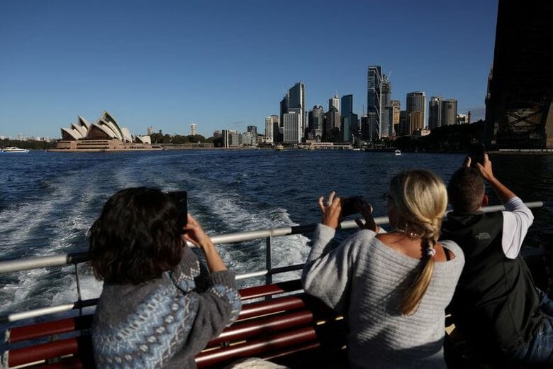 シドニー・オペラハウスと中心業務地区（ＣＢＤ）の写真を撮る人々。２０２５年７月、豪シドニーで撮影。REUTERS/Hollie Adams
