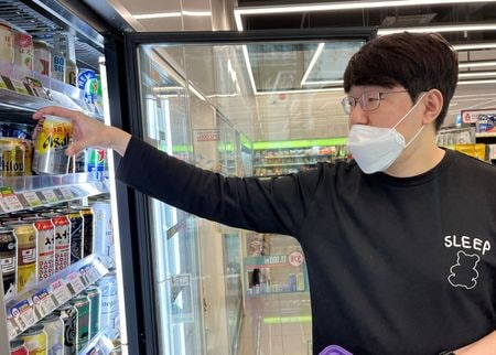 　５月３１日、会社員のジョン・セアーさん（２４歳）は、韓国の芸人が演じる日本人ホスト、「タナカ」を見ると幸せな気持ちになる。写真は５月、ソウルのコンビニエンスストアで「アサヒスーパードライ 生ジョッキ缶」を買うソン・インセオクさん（２０２３年　ロイター/Minwoo Park）