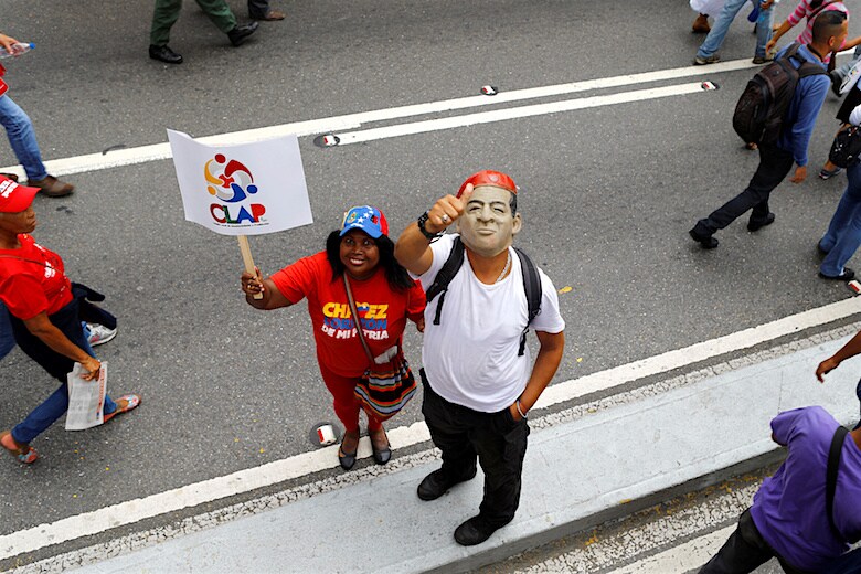 CLAMPのプラカードをかかげ、チャベス支持を示す男女（２０１６年　ロイター／Ivan Alvarado）