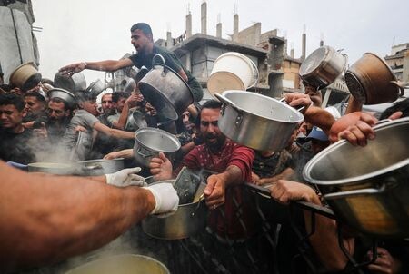 　４月２５日、国連の世界食糧計画（ＷＦＰ）は、パレスチナ自治区ガザは物資搬入ルートが引き続き閉鎖されているために食料の備蓄が底を突いたと発表した。配給を待つ人々、ガザ地区で２４日撮影（２０２５年　ロイター／Mahmoud Issa）