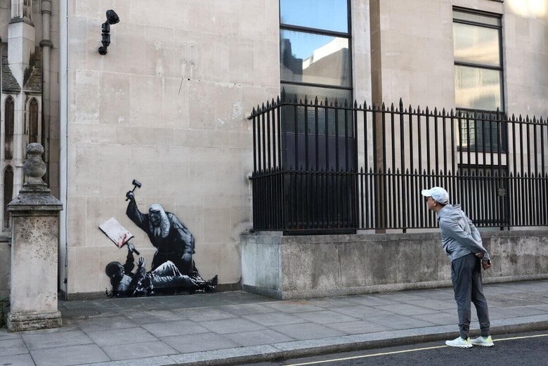 ロンドン王立裁判所の外壁に描かれたバンクシーの新作を眺める通行人（9月9日）　Toby Melville-Reuters