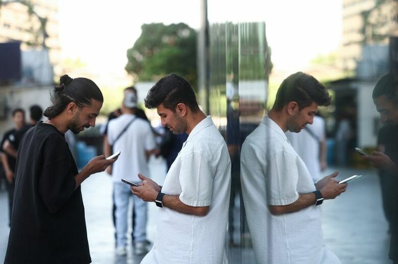 2026年5月27日、イランのテヘランで、国際インターネット接続の再開が報告された後、携帯電話を使用する男性。Majid Asgaripour/WANA (West Asia News Agency) via REUTERS