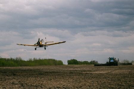 　重要な北米の収穫期を前に、カナダのマニトバ州から米インディアナ州にかけて穀物の種まきに遅れが出ており、生産量の落ち込みを懸念する声が上がっている。写真はマニトバ州で、飛行機で畑にキャノーラをまき、トラクターで作物を植えている農家の人々。５月２７日撮影のStefanie Lepp氏提供写真（２０２２年　ロイター）