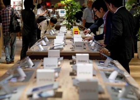 　２月７日、公正取引委員会は、大手携帯電話会社に販売手法の是正や機能開放などを求めた報告書「携帯電話市場における競争政策上の課題について」のフォローアップを開始すると発表した。写真は陳列されたスマートフォンを見る客。昨年６月、東京のＮＴＴドコモの店内で撮影（２０１８年　ロイター／Toru Hanai）