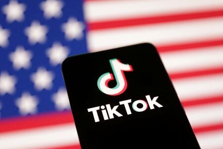 中国系動画投稿アプリ「ＴｉｋＴｏｋ（ティックトック）」の米国内での利用を禁止する新たな法律を巡り、米ＮＢＣニュースは１月１５日、バイデン米政権が、新法が１９日に発効しても引き続きアクセスできる方法を模索していると関係者情報として報じた。米国の旗を背景にティックトックのロゴを８日撮影（２０２５年　ロイター/Dado Ruvic）