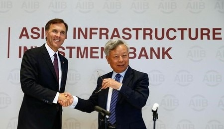 ８月３１日、カナダは、中国主導のアジアインフラ投資銀行（ＡＩＩＢ）への加盟を申請する。写真は握手するモルノー財務相（左）と金立群ＡＩＩＢ総裁、北京で撮影（２０１６年　ロイター/Thomas Peter）