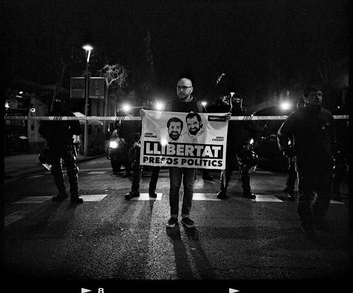 プッチダモン前首相の身柄拘束に抗議する独立派の大規模デモ。機動隊の前で「政治犯釈放」の旗を掲げるデモ参加者（3月23日、バルセロナ）　Photograph by Toru Morimoto