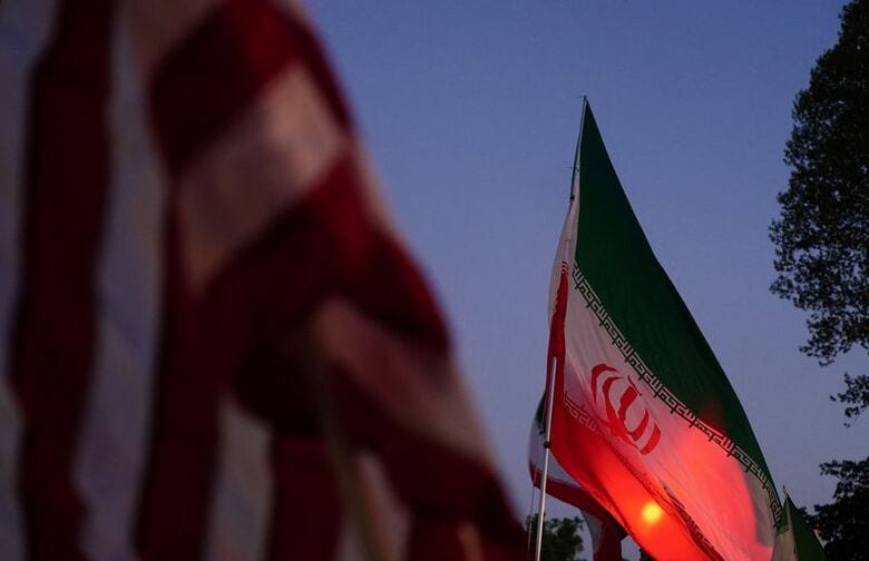 イラン軍事行動に反対するデモで掲げられたイランと米国の国旗。４月７日、ワシントンで撮影（２０２６年　ロイター/Nathan Howard）