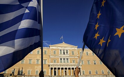 ギリシャ国旗（左）とＥＵの旗を掲げて国会議事堂に向かう人々　Yannis Behrakis-REUTERS